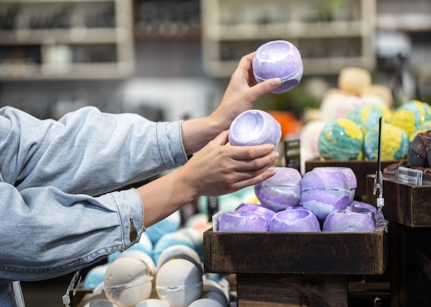 Vrouwelijke handen houden heldere badbommen in een cosmetica-winkel. lichaamsverzorging concept.