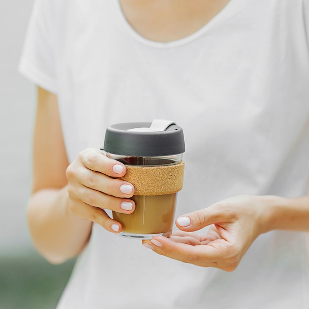 Vrouwelijke handen houden herbruikbare koffiemok vast. Duurzame levensstijl. Milieuvriendelijk concept.