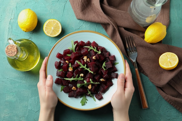 Vrouwelijke handen houden plaat van smakelijke bietensalade, bovenaanzicht