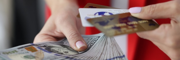 Vrouwelijke handen houden veel dollarbiljetten vast en plastic bankkaarten close-up