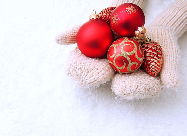 Vrouwelijke handen in wanten kerstboom ballen, op kleur achtergrond