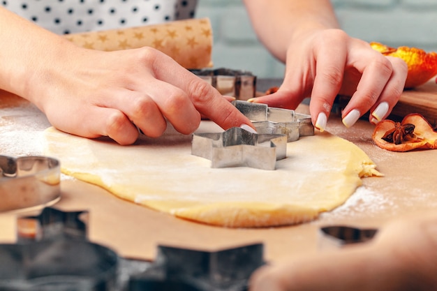 vrouwelijke handen maken van koekjes van vers deeg thuis