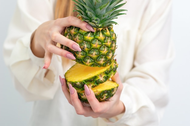 Vrouwelijke handen met ananas in sectie, close-up.