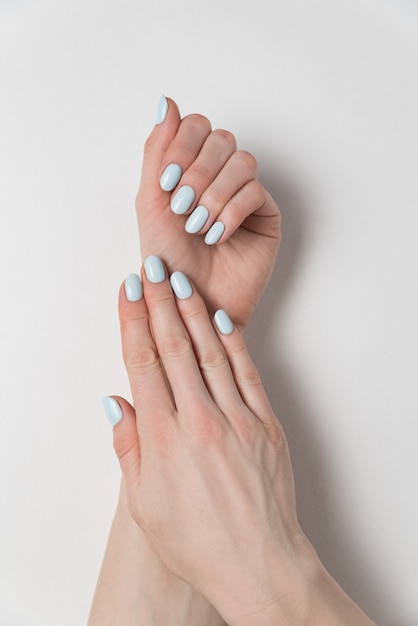 Vrouwelijke handen met delicate blauwe manicure. Gel Pools. Wit oppervlak