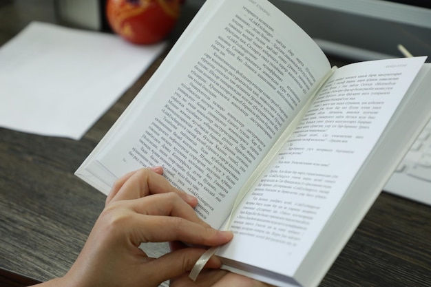 Vrouwelijke handen met een boek op een houten tafel in de bibliotheek