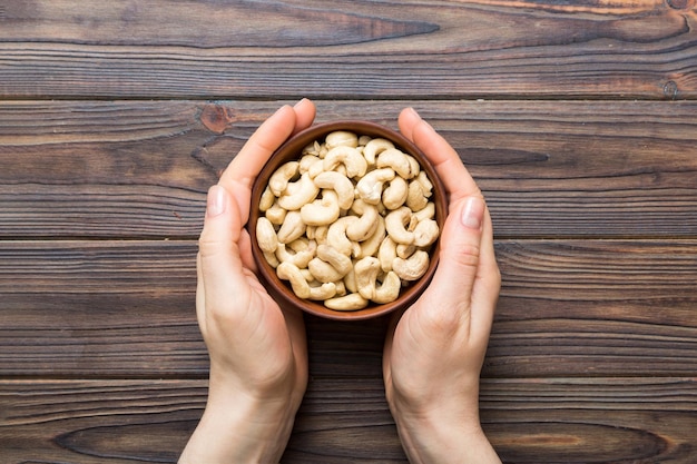 Vrouwelijke handen met een houten schaal met cashewnoten Gezond eten en snacks Vegetarische snacks van verschillende noten
