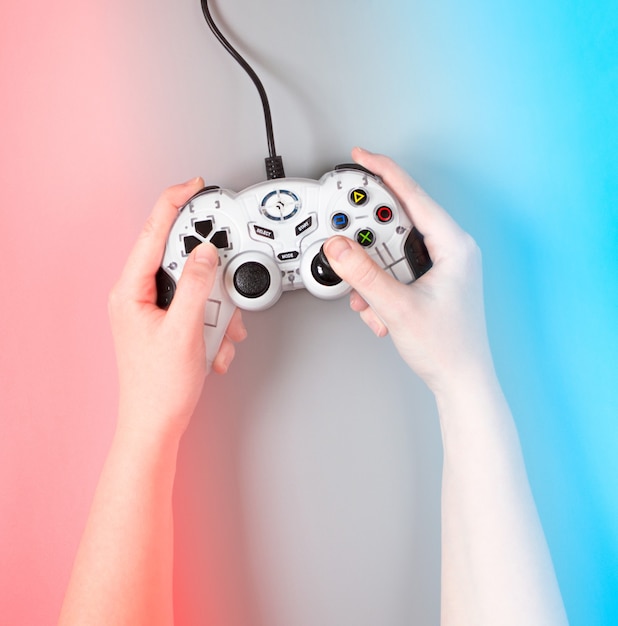 Vrouwelijke handen met een joystick van het spel op blauwe en rode ondergrond.