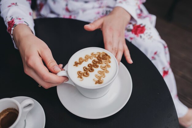 Vrouwelijke handen met een kopje koffie met boven tafel, bovenaanzicht