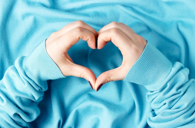 Vrouwelijke handen met een manicure in de vorm van een hart op een blauwe achtergrond