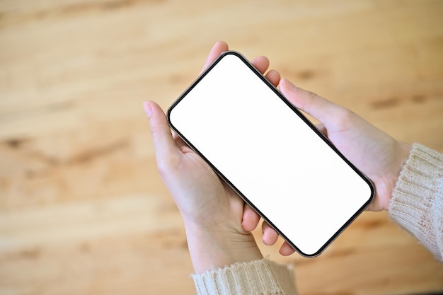 Vrouwelijke handen met een mobiel wit schermmodel over houten achtergrond