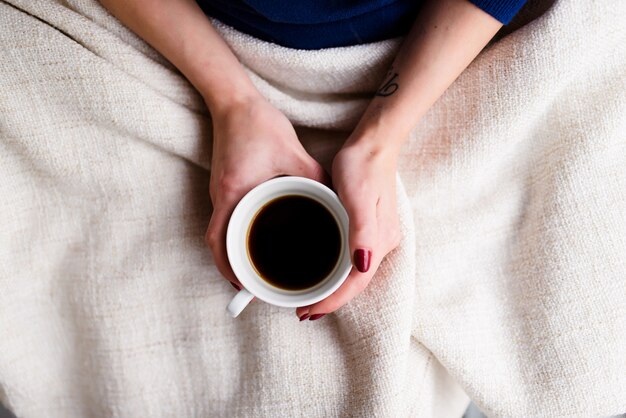 Vrouwelijke handen met een mooie manicure houden een kopje koffie