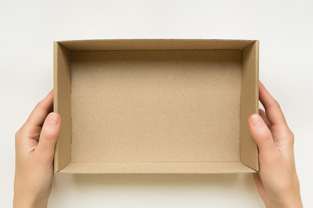 vrouwelijke handen met een open kartonnen doos op een witte achtergrond verpakking en levering concept