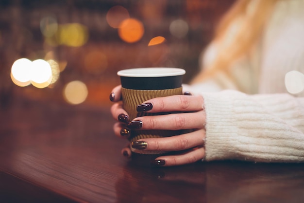 Vrouwelijke handen met een papieren beker met hete koffie