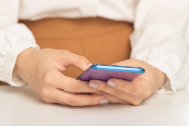 Vrouwelijke handen met een smartphone aan tafel doen boodschappen via mobiel scherm