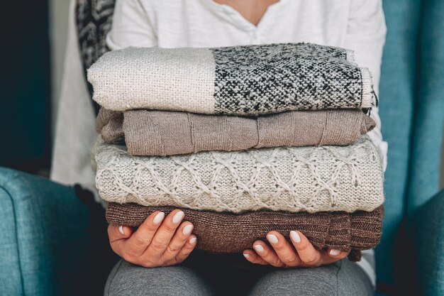 Vrouwelijke handen met een stapel warme gebreide kleding