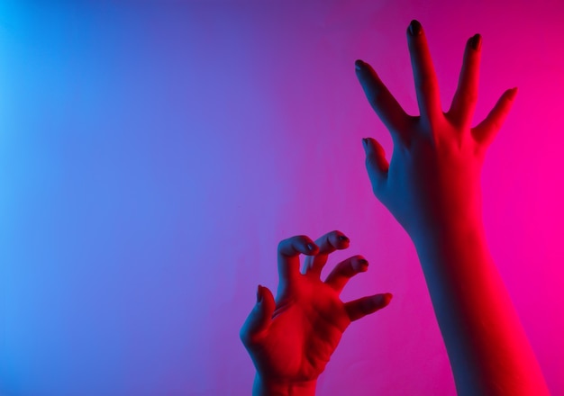 Vrouwelijke handen met enge gebaren. neon blauw-roze kleurverloop
