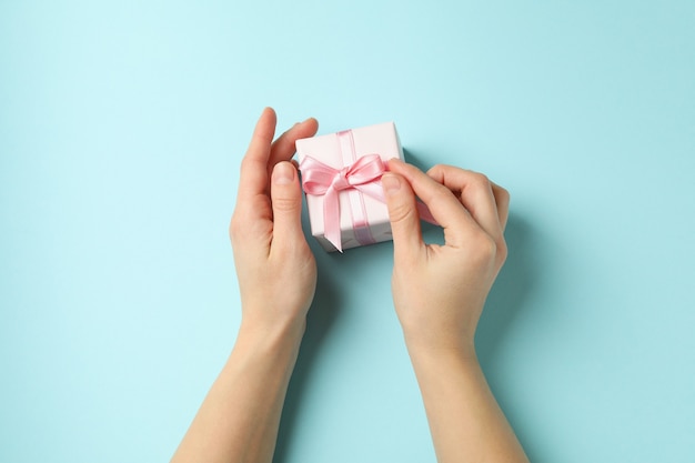 Vrouwelijke handen met geschenkdoos met roze lint op blauwe achtergrond