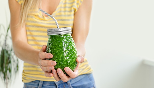 Foto vrouwelijke handen met groene groente smoothie pot. detox dieet concept. kopieer ruimte