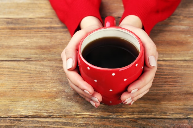 Vrouwelijke handen met kopje koffie op houten achtergrond