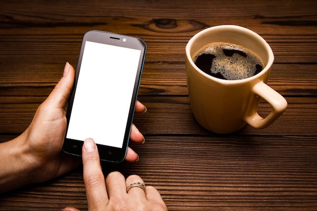 Vrouwelijke handen met kopje koffie op houten tafel