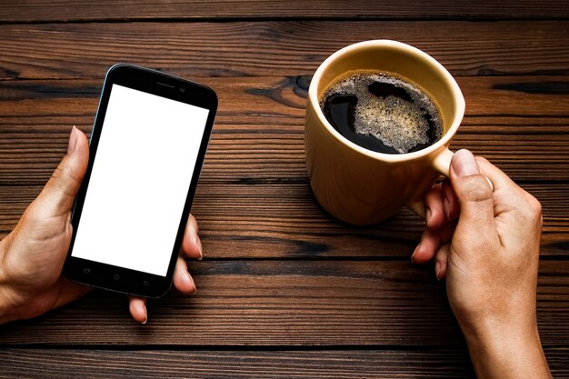 Vrouwelijke handen met kopje koffie op houten tafel