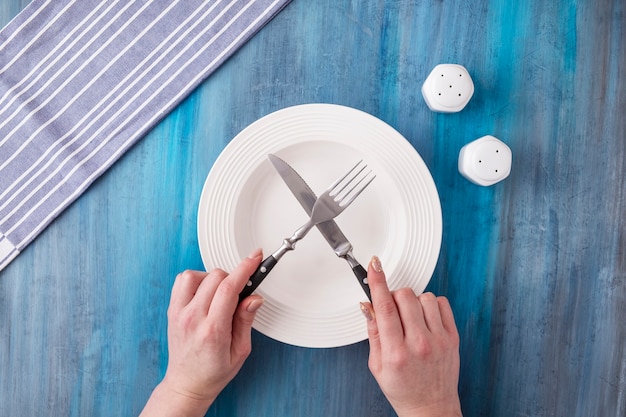 Vrouwelijke handen met mes en vork over witte plaat