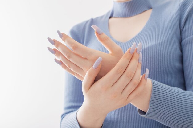 Vrouwelijke handen met mooie blauwe manicure op witte achtergrond