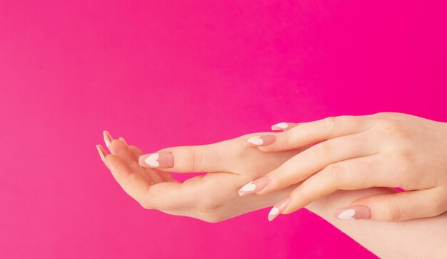 Vrouwelijke handen met mooie lange nagels met manicure met hartpatroon op roze achtergrond