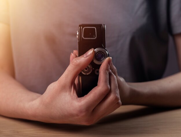 Vrouwelijke handen met oude antieke vintage filmcamera retro fotolens