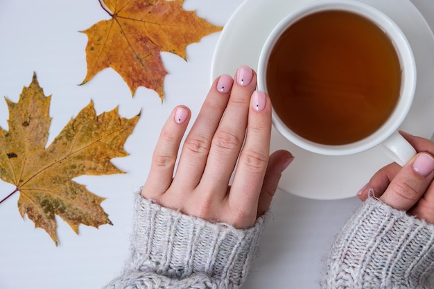 Vrouwelijke handen met prachtige naakte manicure die herfstbladeren vasthouden vrouwelijke manicure natuurlijke nagels