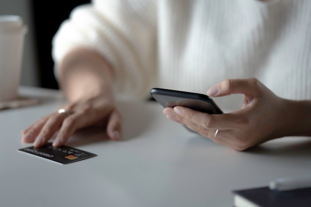 Vrouwelijke handen met smartphone met creditcard op tafel Online winkelen