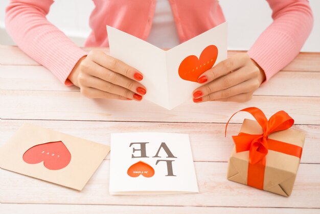 Vrouwelijke handen met Valentijnsdag liefdesbrief op houten achtergrond.