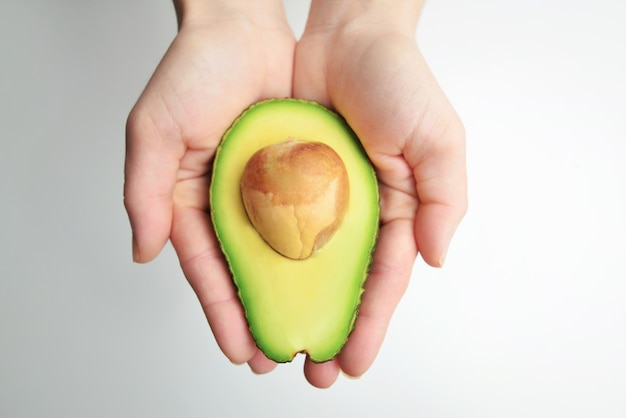 Vrouwelijke handen met verse avocado, close-up.