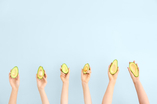 Vrouwelijke handen met verse avocado's op lichte achtergrond