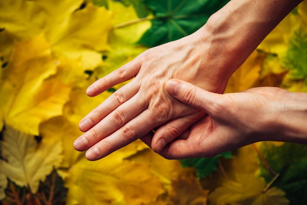 Vrouwelijke handen met vervagende huid close-up op onscherpe achtergrond van herfst gebladerte