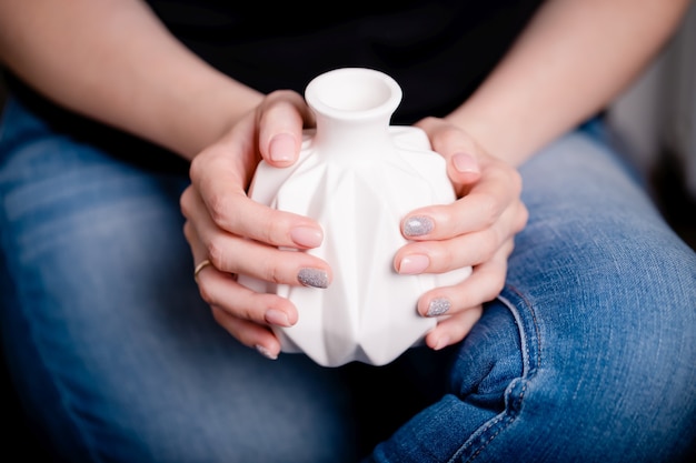 Vrouwelijke handen met witte keramische vaas