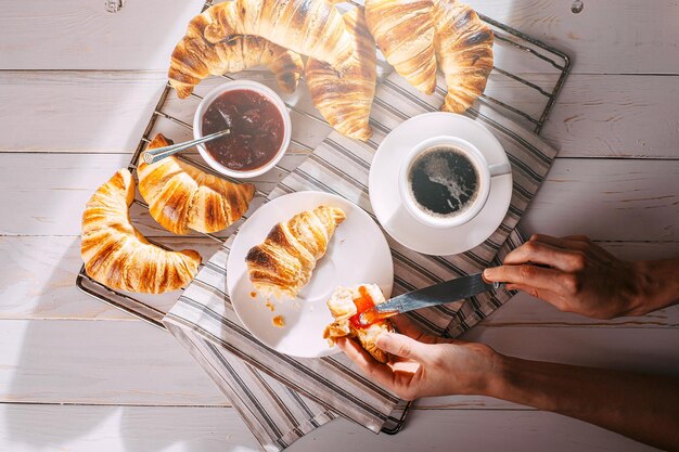 Vrouwelijke handen op croissant spread jam