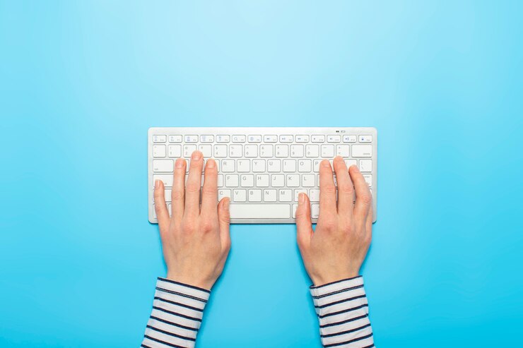 Vrouwelijke handen op een toetsenbord op een blauwe achtergrond. Freelance concept van kantoorwerk, online.