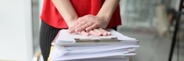 Vrouwelijke handen rusten op een stapel mappen en documenten een close-up van de tafel van het kantoor