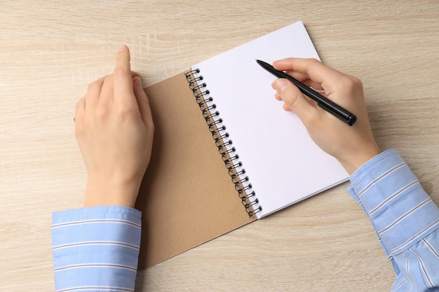 Vrouwelijke handen schrijft in blanco notitieboekje op houten tafel