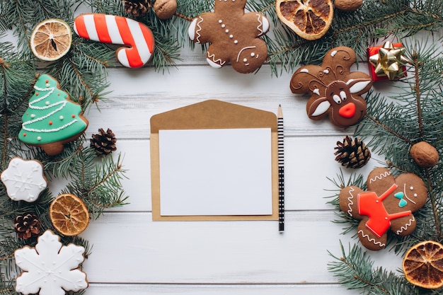 Vrouwelijke handen schrijven een gastvrije kerstkaart op een gengerbread en geschenken achtergrond.