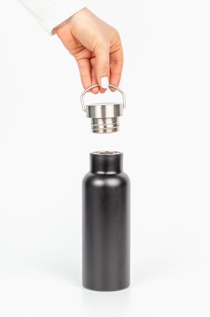 Vrouwelijke handen sluiten een metalen herbruikbare fles voor water
