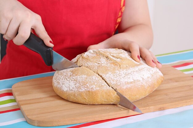 Vrouwelijke handen snijden brood in de keuken