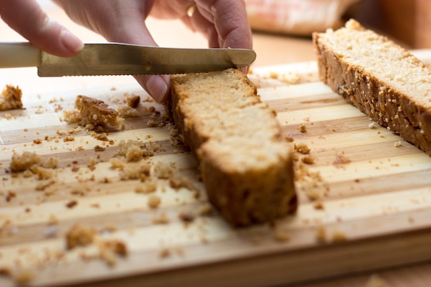 Vrouwelijke handen snijden en bereiden taartkorst op houten plaat