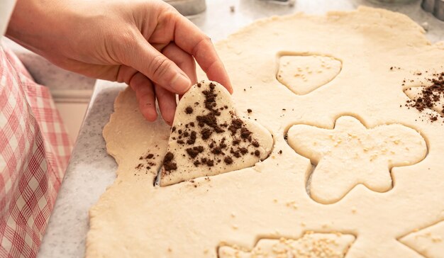 Vrouwelijke handen snijden vormen en maken kerstkoekjes