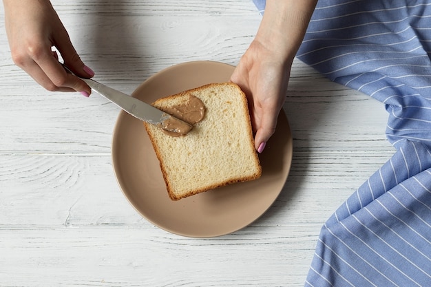 Vrouwelijke handen toast brood met pindakaas verspreiden, waardoor gezond ontbijt, bovenaanzicht