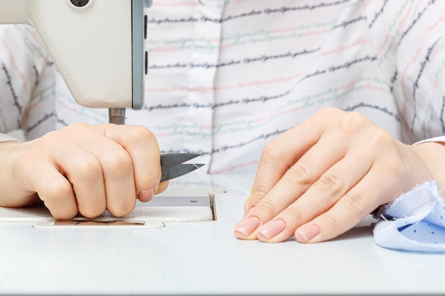 Vrouwelijke handen van een meester-kleermaker knipt een draad met een schaar