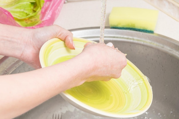 Vrouwelijke handen wassen de borden Huiswerk in de keuken Creëren van netheid en orde