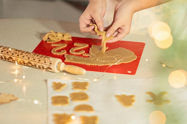 Foto vrouwelijke handen zetten vers gemaakte peperkoekkoekjes in een bord in de vorm van een kerstboom