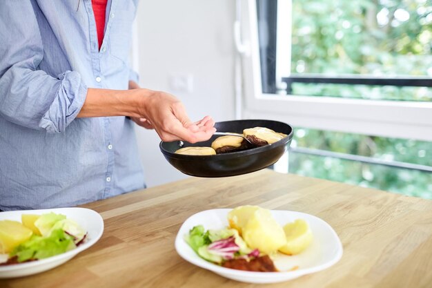 Vrouwelijke handen zwarte pan gekookte aardappelen Vrouw legt eten op borden Thuisgemaakt diner